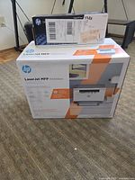 Front view of sealed HP LaserJet MFP M234dwe printer box with toner cartridge box on top
