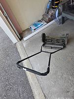 Overall view of reel mower folded, showing handle and wheels