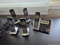 Group shot of base unit with handset and four additional handsets in charging cradles
