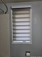 Single zebra roller blind mounted above bathroom window with pull cord visible