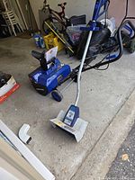 Snow blower and power shovel on garage floor