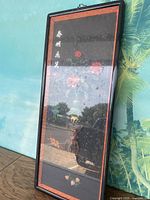 Photo of the entire framed artwork leaning against a wall showing the rectangular frame and overall appearance.