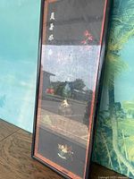 Full view of the vertically oriented framed artwork showing the black frame with red inner border, floral design with jade accents, and Chinese script at the top.