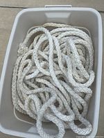 Coiled white braided rope inside a container, shows length and condition.