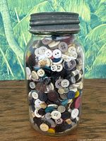 Full view of antique Kerr Mason jar filled with assorted buttons, showing lid and button variety inside.