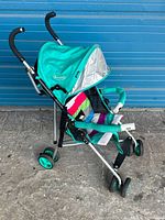 Full side view of EQ baby stroller with turquoise canopy, striped fabric seat and safety features.