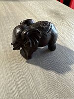Photo of the darkwood hand carved elephant figurine showing detailed carving on top and side profile with lighting that highlights its smooth finish and texture.