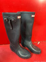 Pair of black Hunter River rubber boots shown side by side, displaying overall shape and exterior details including adjustable strap and buckles.