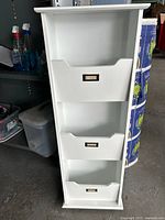Front view of white 3-tier shelf organizer with three pull-out bins and label holders.