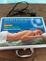Spa hot stone heating box with power cord on top of the metal case, showing branding and product details.