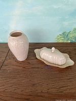 Set showing both Lennox flower bud vase and butter dish on wooden surface against blue wall