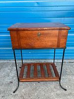 Front view of the wooden cabinet box on iron frame showing front face, keyhole, and lower shelf.