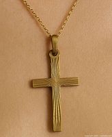 Front view of 10K gold cross pendant showing sunburst engraved pattern.
