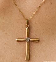 Cross pendant worn on neck showing the gold and diamond detail.