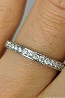 Close-up photo of the ring on a finger showing the CZ stones and band finish.