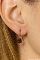 Close-up image showing the earring worn on ear illustrating size and style with deep red garnet in gold setting.