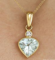 Pendant hanging on fine gold chain against flesh-tone background