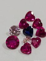 Front angle image showing all stones including round light pink, round pink, heart-shaped dark blue, and multiple heart-shaped pink/red stones.