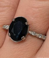 Oval sapphire ring on finger, front view showing setting