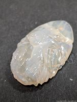 Close-up front angle of the carved genuine opal gemstone showing detailed carving and color play.