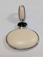 Front view of the silver pendant showing the large opal oval, small black onyx oval, and bail with elongated opal.