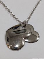 Close-up of double heart pendants showing polished reflective silver surface and chain links