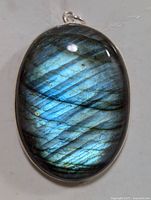 Close-up front view of oval labradorite pendant with bright blue iridescence and silver bezel setting.