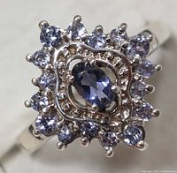 Close-up front view of sterling silver ring showing oval Iolite center stone and surrounding round Tanzanite stones with detailed claw-prong setting
