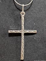 Front view of the sterling silver cross pendant showing the engraved design and silver chain.