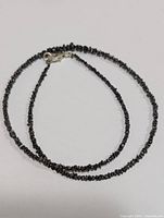 Full view of single-strand black diamond bead necklace with silver clasp laid flat