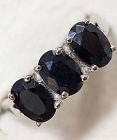 Close-up view of the sterling silver sapphire ring showing three oval-cut dark blue sapphires in prong settings.