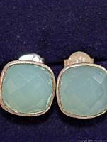 Close-up front view of a pair of square faceted chalcedony stones set in sterling silver bezel studs