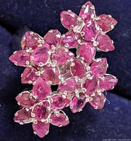Close-up photo showing the cluster arrangement of multiple red ruby stones set on silver ring top in floral design.