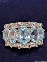 Close-up top-down view showing the five oval blue topaz stones and two rows of cubic zirconia along the band
