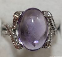 Close-up of the oval cabochon amethyst set in a sterling silver ring with a beaded textured band.
