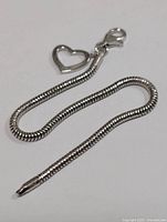 Photo of the entire silver bracelet highlighting the snake chain and heart charm
