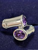 Close-up view of the sterling silver amethyst ring showing the two oval faceted purple amethyst stones set in bezel mountings in a bypass style design.
