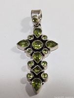 Close-up front view of sterling silver cross pendant with multiple peridot stones.