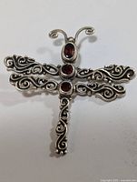 Front view of sterling silver butterfly pendant showing ornate filigree wings and garnet stones