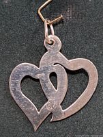 Front view of silver pendant showing the interlocking heart design with hammered texture and loop at the top.
