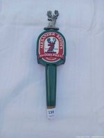 Front view of Alexander Keith's tap handle showing logo, green body, metal stag finial