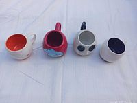 Top view of four mugs showing interiors: orange, red, grey, navy