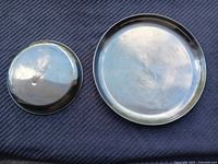 Top view of a stainless steel lid and shallow plate showing polished finish