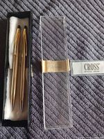 Pen, pencil in felt-lined insert next to clear Cross box