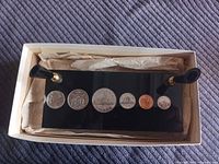 Pen holder in box showing coins and pen sockets