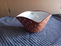 Angled view of bowl showing brown polka-dot exterior and white interior