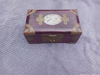 Closed wooden jewelry box showing brass fittings and carved lid insert