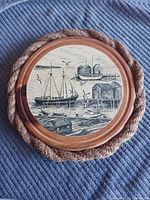 front of circular pine plaque showing maritime illustration, rope border visible
