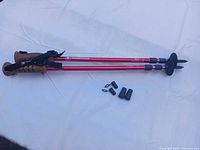 two red SwissGear trekking poles with accessories on white cloth