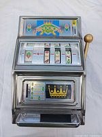 Front view of slot machine showing reels, graphics, lever, payout tray